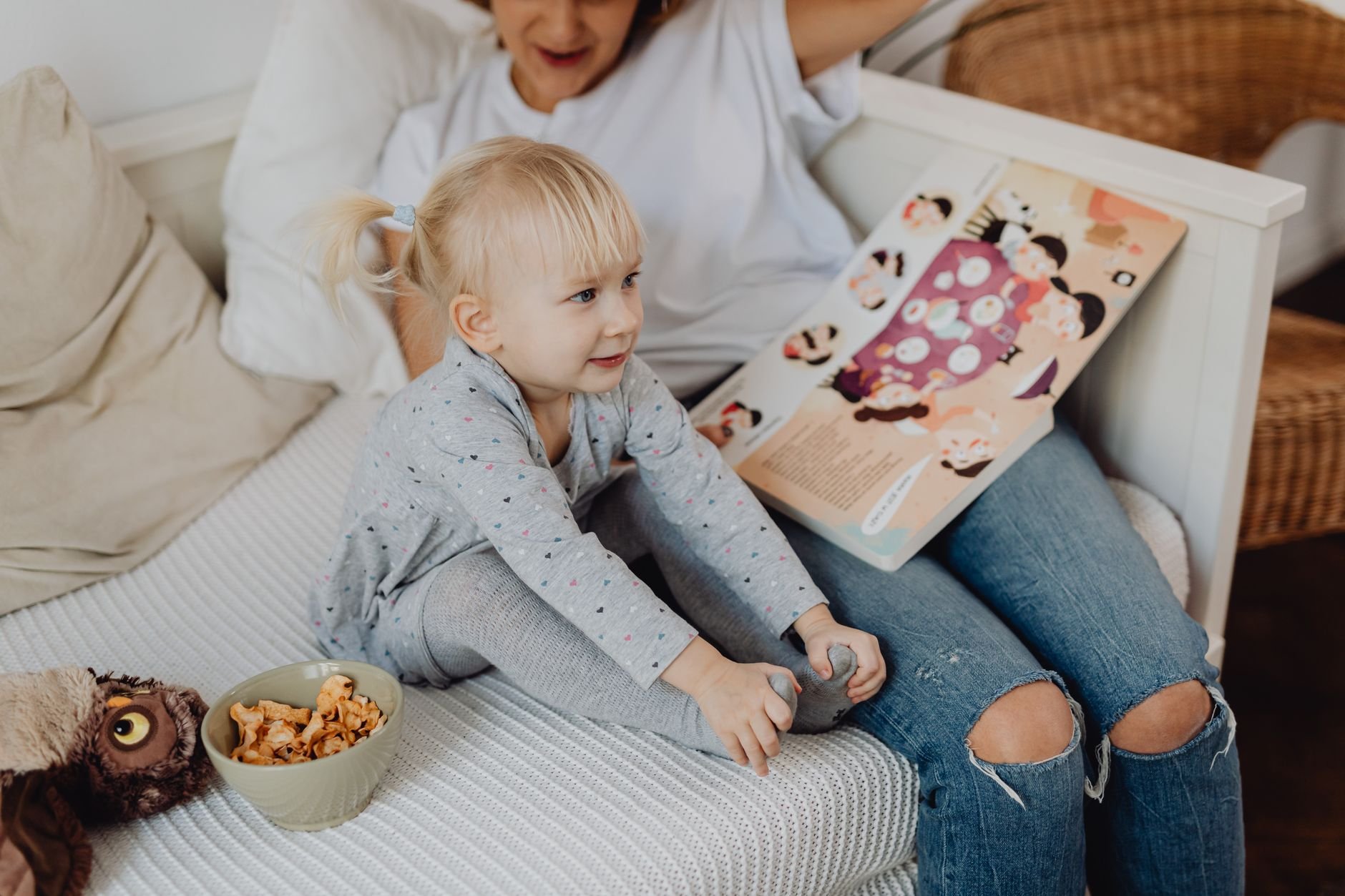 A young child enjoys reading with a caregiver on a cosy sofa
